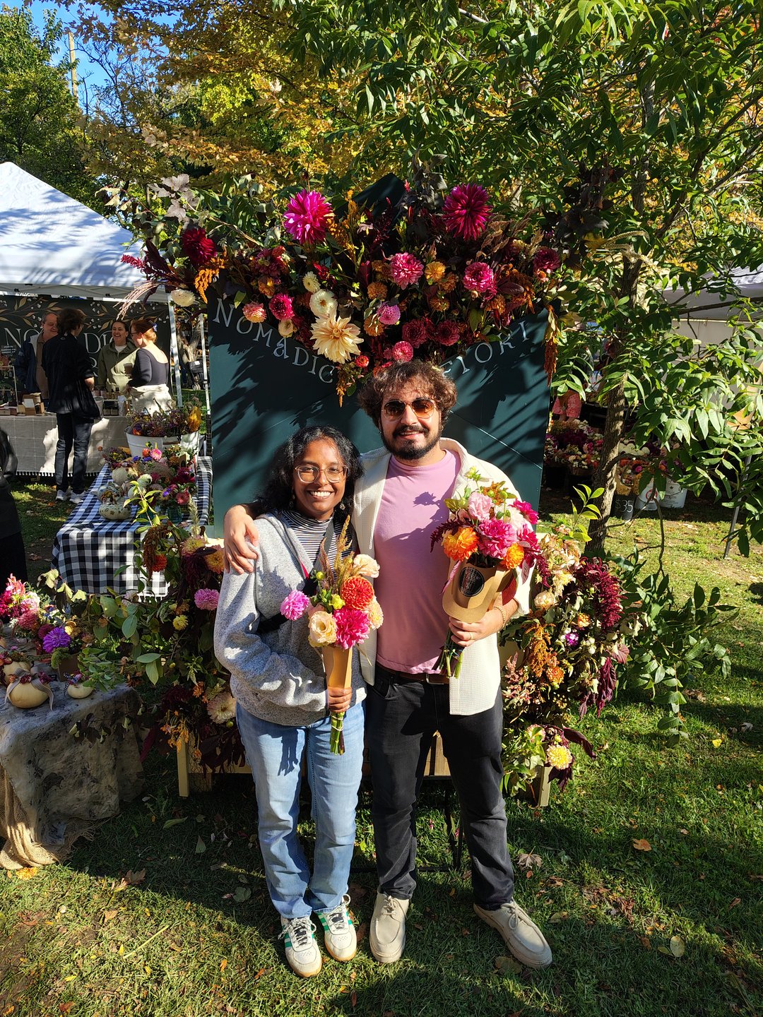 Chris and Aarani surrounded by dahlias at a flower market